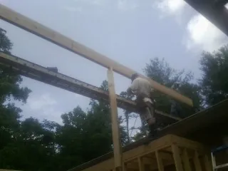 Carpenter setting a ridge beam over a new addition frame — Ice Dam Removal by Roofing Brothers in Glen Echo