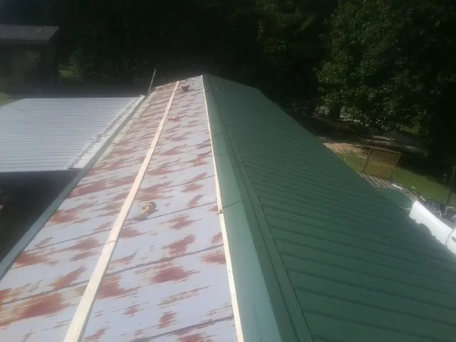 Old rusted panels beside newly installed green metal roofing — Wind Damage Roof Repair by Roofing Brothers in Glen Echo