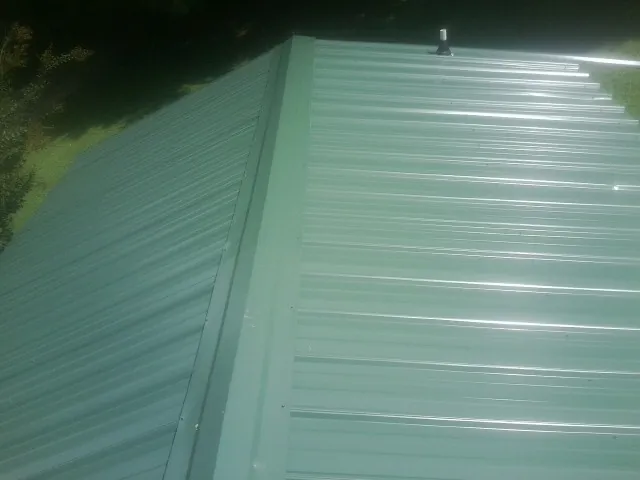 New green metal panels meeting at the ridge of a roof — Flat Roof Repair work by our crew in Glen Echo