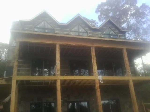 Dormers and porch framing on a large log home under construction — Roof Coating work by our crew in Glen Echo