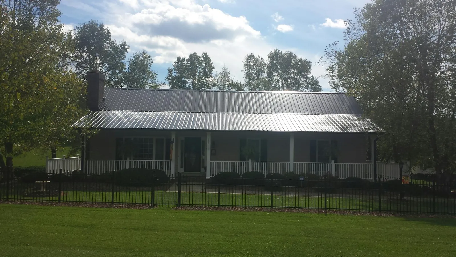 Gray metal roof on a brick ranch with a full width front porch — Gutter Guard Installation work by our crew in Glen Echo